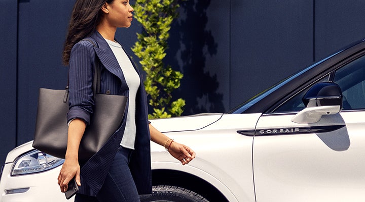 A woman approaches a 2024 Lincoln Corsair® SUV while holding a smartphone. | Sheehy Lincoln of Richmond in Richmond VA